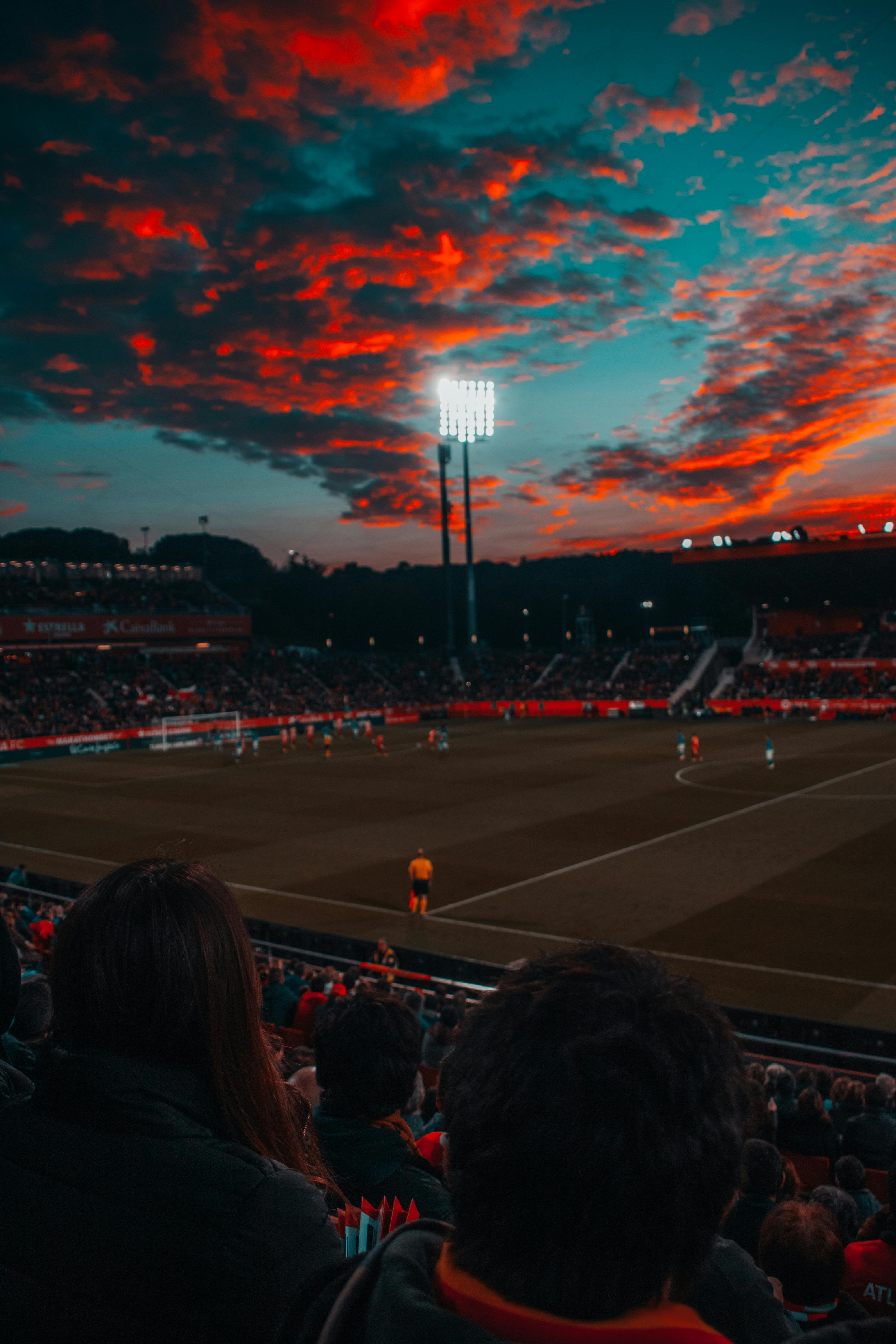 “A football field under a dramatic red sky, symbolizing the ever-evolving game and the unseen mental battles that take place beyond the pitch.”